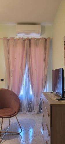 a room with a window with pink curtains and a chair at Bed & Breakfast da Giovanni in Alessano
