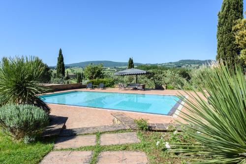 una piscina en un jardín con mesa y sombrilla en Villa San Gimignano View, en Strada