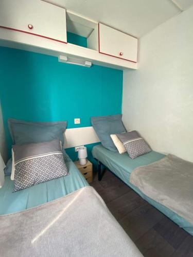 - 2 lits dans une petite chambre aux murs bleus dans l'établissement Mobil home de charme à la mer, à Fréjus