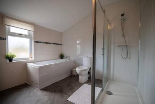 a bathroom with a tub and a toilet and a shower at Spacious Town House in Lytham St Annes
