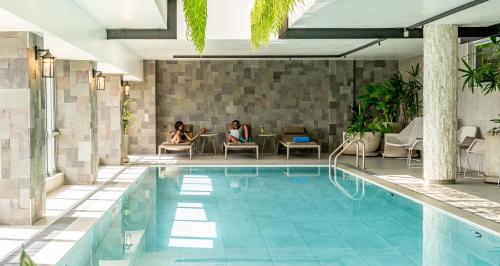 dos mujeres sentadas en una mesa junto a una piscina en Dusit Princess Hotel Residences Nairobi en Nairobi