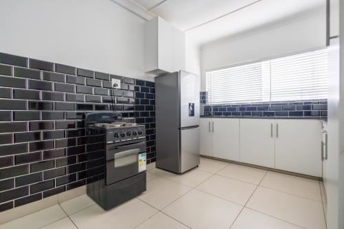イースト・ロンドンにあるSafi Luxury Apartment 6 - 2 bedroomの黒いタイルの壁のキッチン(コンロ付)