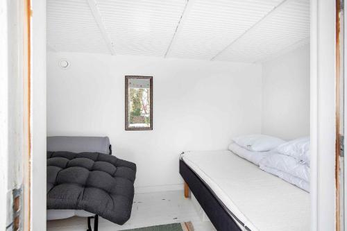 a small bedroom with a bed and a chair at Lovely Bright Summer House Close To The Beach in Rødvig