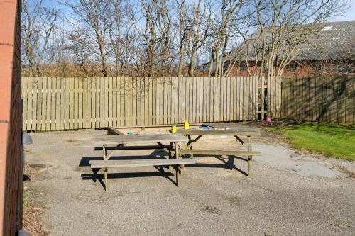a picnic table and benches in front of a fence at House For 40 People Near Thy in Gettrup