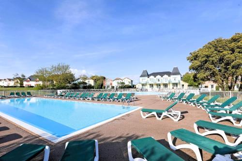 une piscine avec des chaises longues vertes et un tas de meubles dans l'établissement Alouette Piscines chauffees, à Saint-Hilaire-de-Talmont