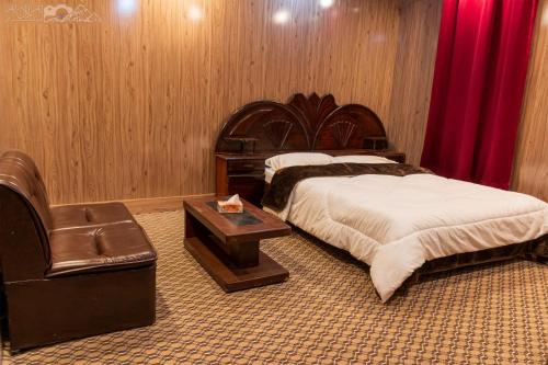 1 dormitorio con 2 camas, mesa y silla en Ghanchi Inn Hotel en Dargai