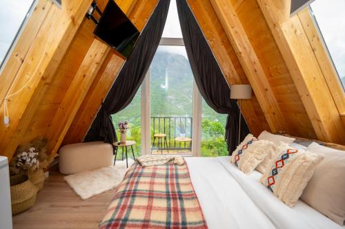 ein Schlafzimmer mit einem Bett und einem großen Fenster in der Unterkunft Vidis Chalet Hotel in Theth