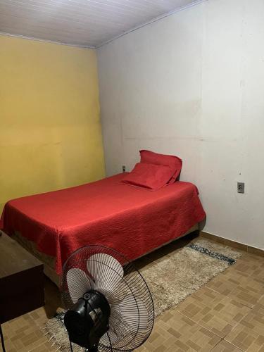 Schlafzimmer mit einem roten Bett und einem Ventilator in der Unterkunft Apt Rondônia rual show in Ji-Paraná