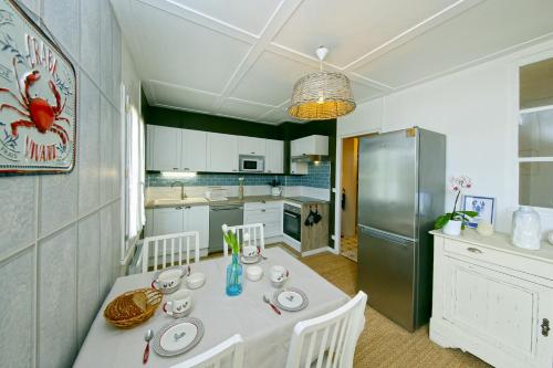Il comprend une cuisine équipée d'une table blanche et d'un réfrigérateur. dans l'établissement Le Cottage du Moulin - 15min du Mont Saint-Michel, à Beauvoir