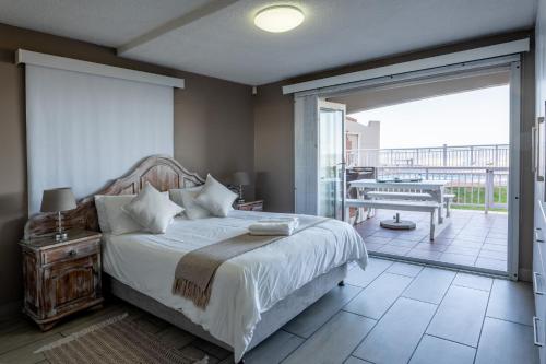 ein Schlafzimmer mit einem Bett und einem Balkon in der Unterkunft Jeffreys Bay Villas on The Beach in Jeffreys Bay
