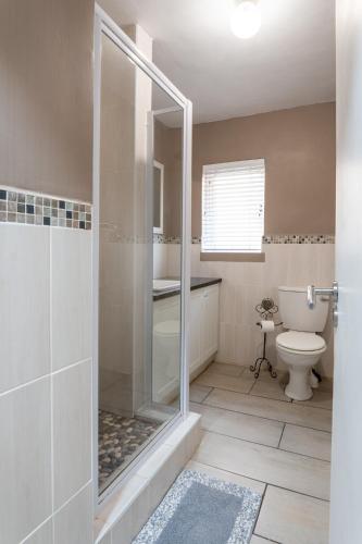 a bathroom with a shower and a toilet at Jeffreys Bay Villas on The Beach in Jeffreys Bay