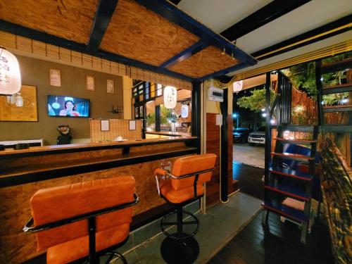 Ban Chak Khamin的住宿－อีโฮสเทลบ้านช่น，餐厅内带橙色椅子的酒吧