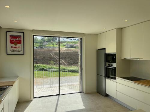 a kitchen with white cabinets and a sliding glass door at PORTO - Penafiel - QUINTA DE SANTIAGO COUNTRY HOUSE in Penafiel