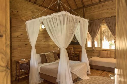 1 dormitorio con 2 camas y cortinas en una cabaña en Hotel la Ardilla de Santa Fe, en Santa Fe de Antioquia