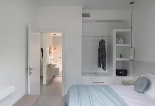 a white bedroom with a bed and a bathroom at The Port in Porto Koufo