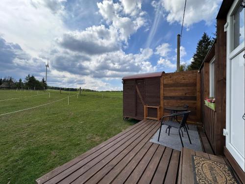 a wooden deck with a table and a field at Horská maringotka na farmě in Klíny