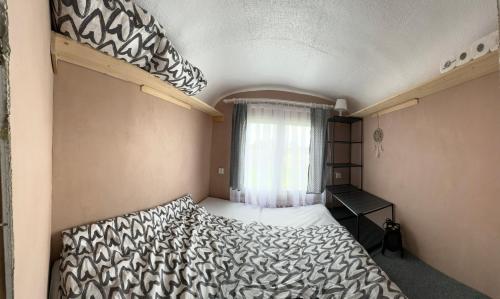 Horská maringotka na farmě في Klíny: غرفة نوم صغيرة مع سرير بطابقين ونافذة