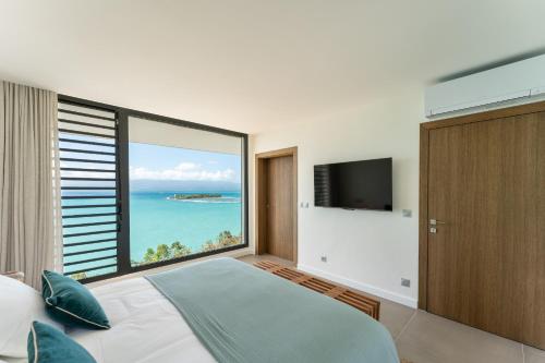 een slaapkamer met een groot raam met uitzicht op de oceaan bij Guacana in Le Gosier