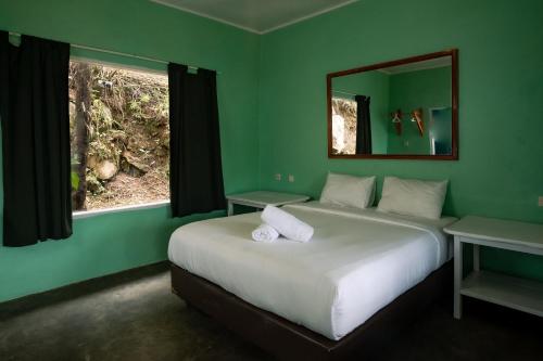 Habitación verde con 2 camas y espejo. en Manulalu B&B, en Bajawa