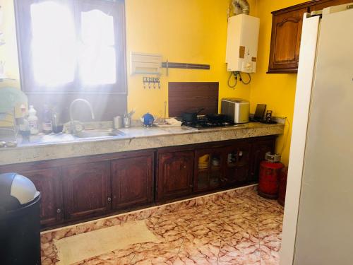 a kitchen with wooden cabinets and a sink and a window at Villa Naoual in Moulay Bousselham
