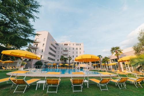 uma piscina com cadeiras e guarda-sóis em frente a um edifício em Hotel Terme Helvetia em Abano Terme