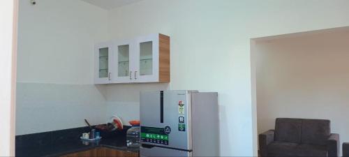 a kitchen with a stainless steel refrigerator and a chair at The Heritage Serviced Apartments in Mandya