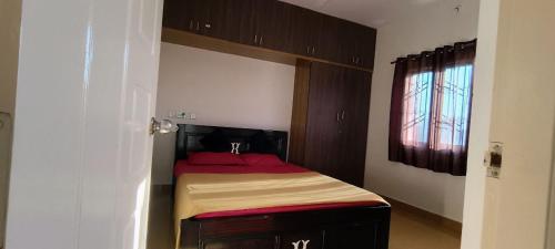 una piccola camera da letto con un letto con lenzuola rosse di The Heritage Serviced Apartments a Mandya