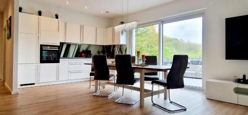 uma cozinha com uma mesa de madeira e cadeiras pretas em Ferienhaus Waldblick em Hohenfels-Essingen