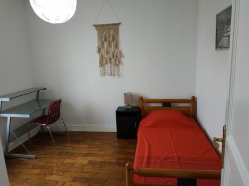 a bedroom with a desk and a bed with a red blanket at Bel appartement proche tous commerces in Nancy
