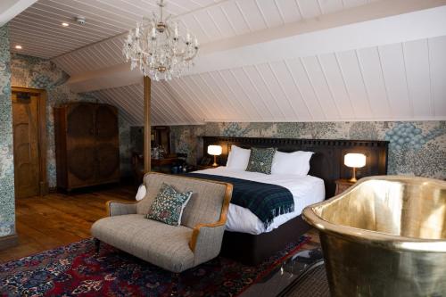 Un dormitorio con una cama, una silla y una lámpara de araña. en The Old Inn, en Crawfordsburn