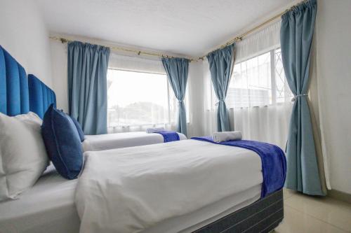 a bedroom with a bed with blue curtains and a window at Safi Smart Self-catering Suite 1 in East London