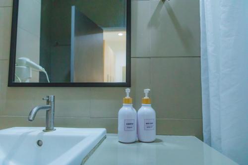 dos botellas sentadas en un lavabo en un baño en Uou Hotel, en Kabin Buri