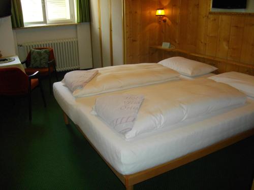 two white beds in a room with a table at Hotel Villa Emilia in Ortisei