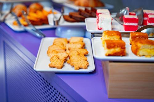 a buffet with plates of food on a purple table at The Match Hotel in Cervia