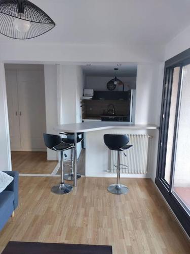 une cuisine avec une table et des tabourets dans une pièce dans l'établissement Appartement de charme au coeur de Perpignan, à Perpignan