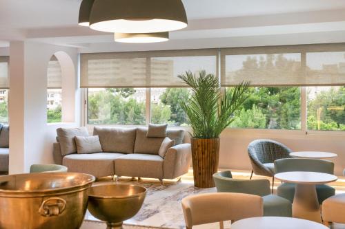 a living room with a couch and tables and chairs at Salles Hotels Marina Portals in Portals Nous