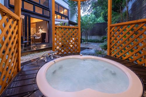 an outdoor hot tub on a deck with a house at Mori no Nanakusa in Munakata