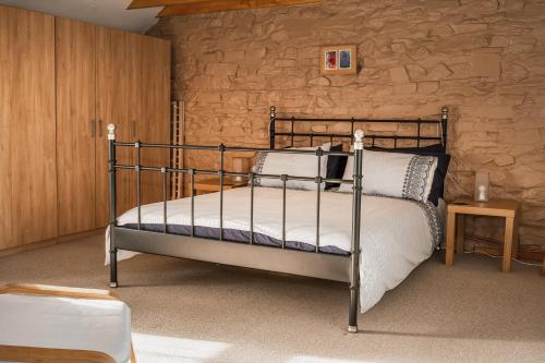 ein Schlafzimmer mit einem Bett und einer Steinwand in der Unterkunft Horseshoe Cottage Aberaeron in Ciliau-Aeron