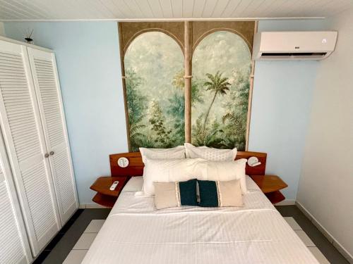 a bed in a room with a painting on the wall at Bungalow La Kawannaise - Piscine, Terrasse, Plage in Grand-Bourg