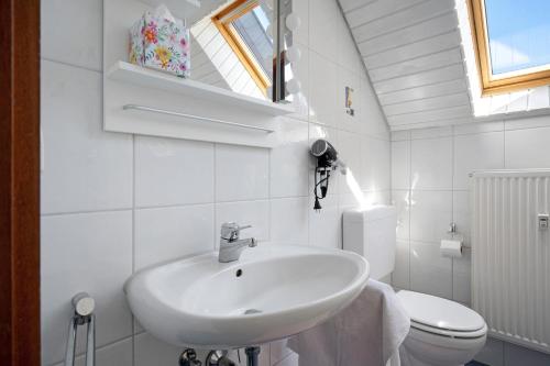 a white bathroom with a sink and a toilet at Ferienwohnung Lange in Waldstetten