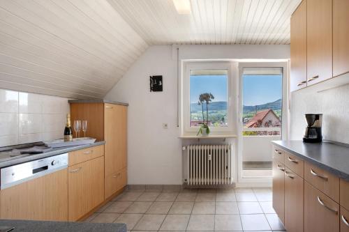 a kitchen with wooden cabinets and a large window at Ferienwohnung Lange in Waldstetten