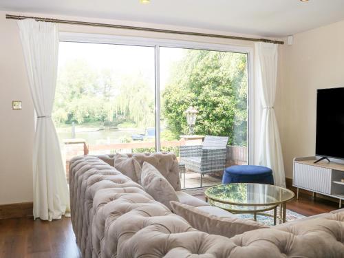 a living room with a large couch and a large window at Coventina in Staines upon Thames