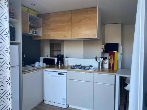 une cuisine avec des appareils électroménagers blancs et des armoires en bois dans l'établissement Bungalow cosy à Vendres avec piscine partagée, à Vendres