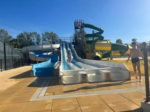 un toboggan aquatique dans un parc aquatique avec des gens dessus dans l'établissement Bungalow cosy à Vendres avec piscine partagée, à Vendres