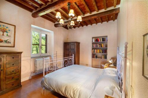 um quarto com uma cama branca e uma estante de livros em Podere a La Fi em Cetona