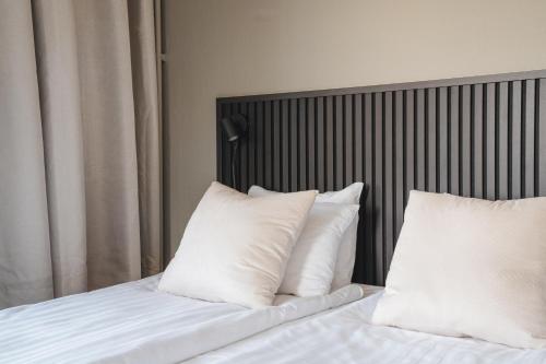 a bed with white pillows and a headboard at VICI Hotels Linköping in Linköping