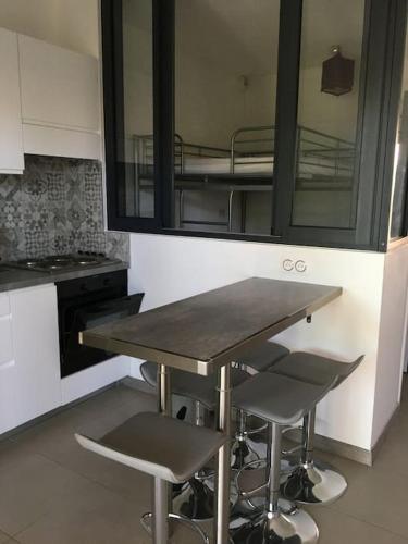 une cuisine avec une table et deux tabourets de bar dans l'établissement Appart, piscine, proche plage, à Lecci
