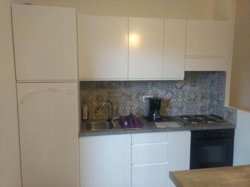 une cuisine avec des armoires blanches et un évier dans l'établissement Appart, piscine, proche plage, à Lecci