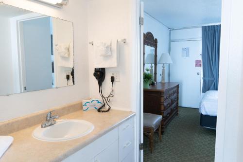 a bathroom with a sink and a bedroom at Beach Club at Montego Inn in Myrtle Beach
