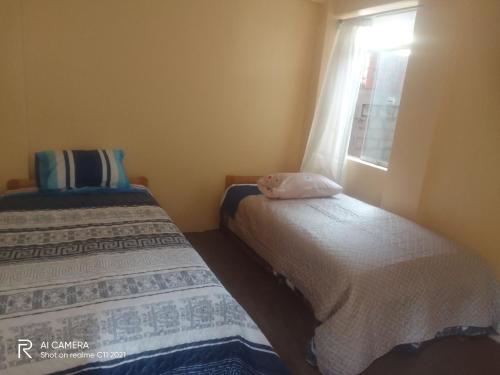 two beds in a room with a window at killa andina inn in Puno